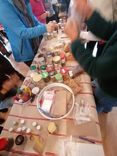 People are gathered around a table covered with various jars of seeds and utensils for the seed workshop.